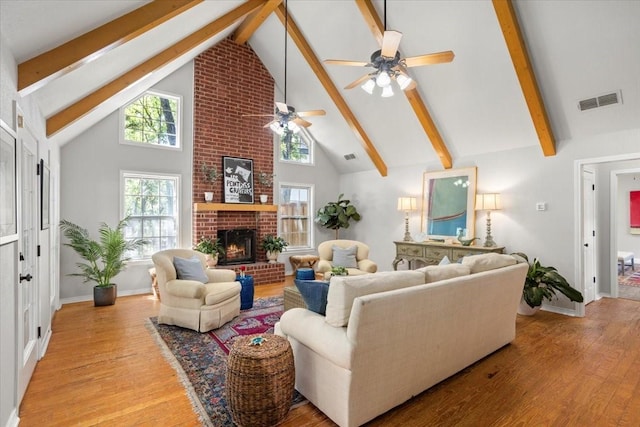 living area with visible vents, light wood-style flooring, ceiling fan, and beam ceiling