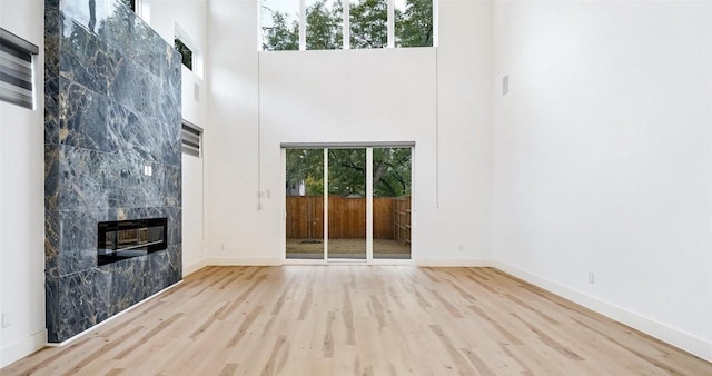 2316 Arroyo Ave, Dallas, TX 75219 - unfurnished living room featuring a high ceiling, wood finished floors, a fireplace, and baseboards