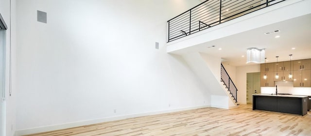 2316 Arroyo Ave, Dallas, TX 75219 - unfurnished living room featuring stairway, light wood-type flooring, baseboards, a towering ceiling, and recessed lighting