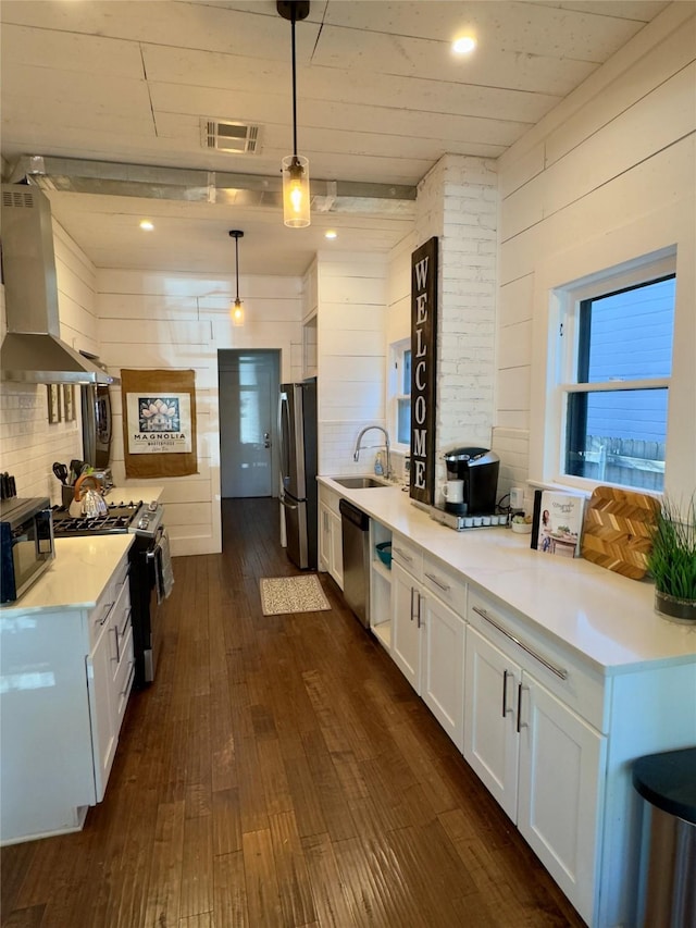 kitchen featuring dark wood-style flooring, appliances with stainless steel finishes, ventilation hood, light countertops, and visible vents