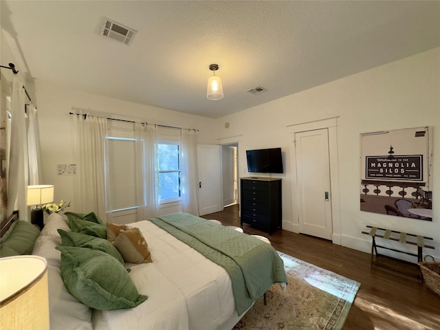 bedroom with visible vents, baseboards, and dark wood-style floors