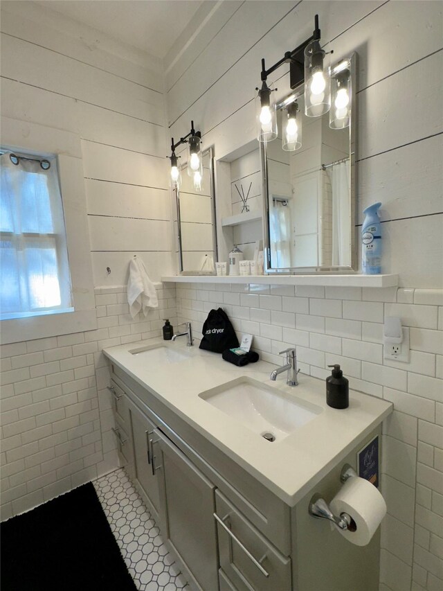 bathroom with double vanity, tile walls, a sink, and tile patterned flooring