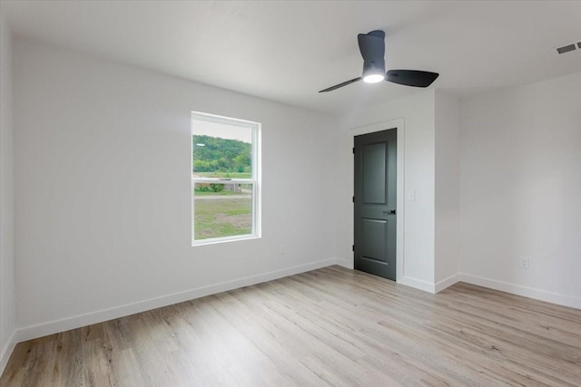 spare room featuring light wood-type flooring, a ceiling fan, baseboards, and visible vents