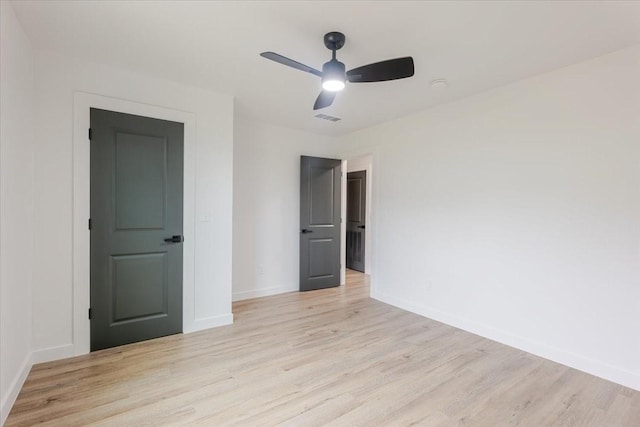 empty room with baseboards, visible vents, ceiling fan, and light wood-type flooring