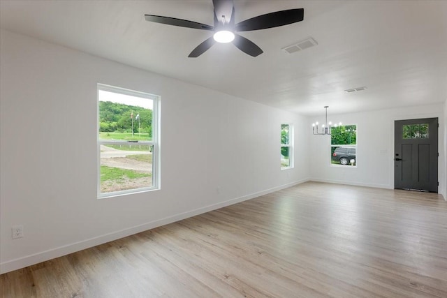 unfurnished room with baseboards, ceiling fan with notable chandelier, light wood-style flooring, and visible vents