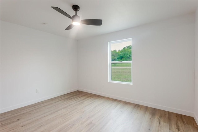 spare room with baseboards, ceiling fan, and light wood finished floors
