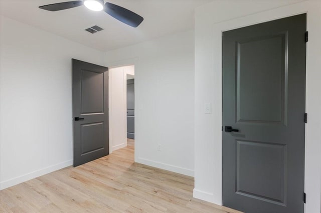 spare room featuring baseboards, a ceiling fan, light wood-style flooring, and visible vents
