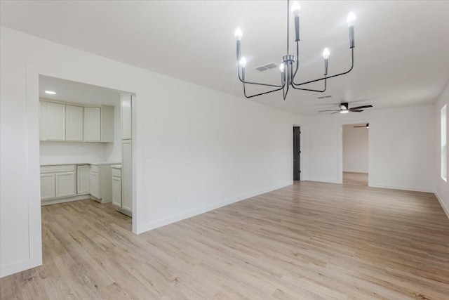 unfurnished dining area with visible vents, baseboards, ceiling fan with notable chandelier, and light wood-type flooring