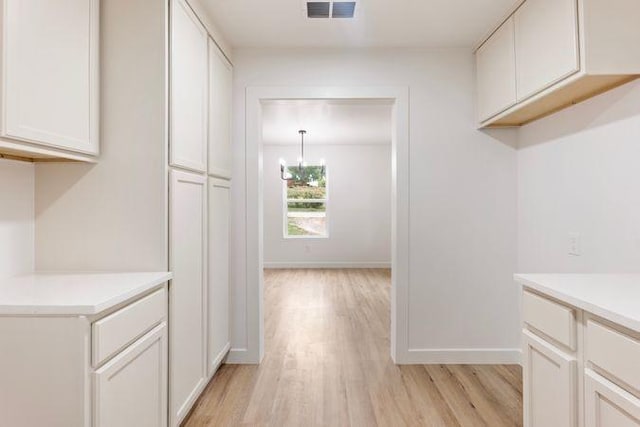 interior space featuring visible vents, light wood finished floors, baseboards, and a notable chandelier