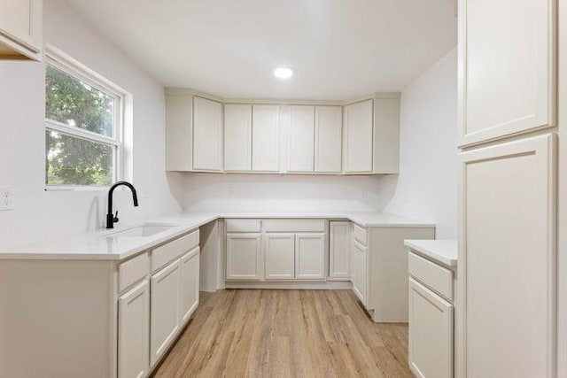 kitchen featuring light countertops, light wood finished floors, recessed lighting, and a sink