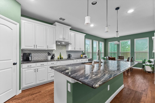 kitchen with black electric stovetop, a sink, decorative backsplash, under cabinet range hood, and dark wood-style floors