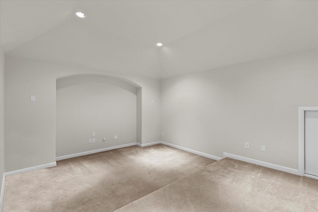 carpeted empty room with recessed lighting, baseboards, vaulted ceiling, and arched walkways