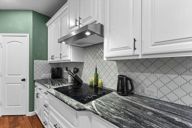 kitchen featuring white cabinets, tasteful backsplash, black electric cooktop, dark wood-type flooring, and under cabinet range hood