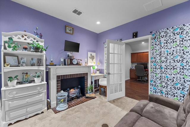 living area featuring carpet flooring, visible vents, french doors, and a fireplace