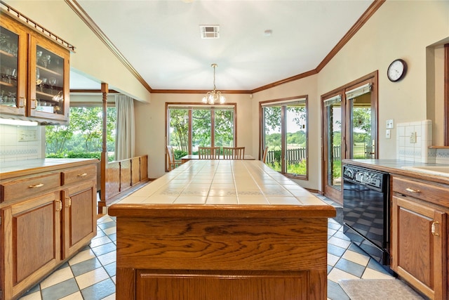 kitchen featuring visible vents, ornamental molding, glass insert cabinets, tile counters, and black dishwasher