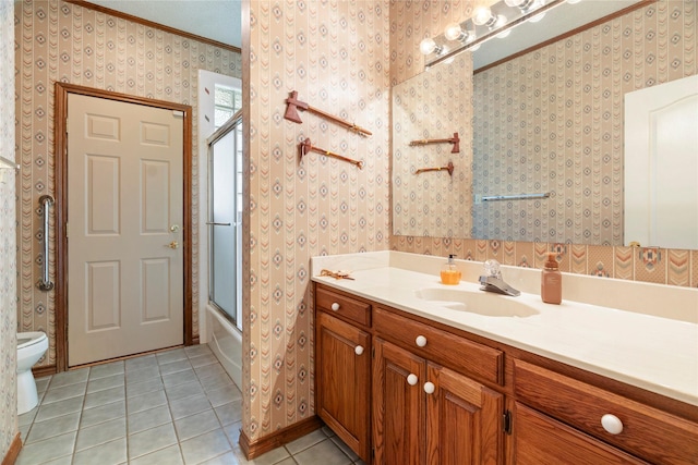 bathroom featuring tile patterned flooring, vanity, shower / bath combination with glass door, toilet, and wallpapered walls