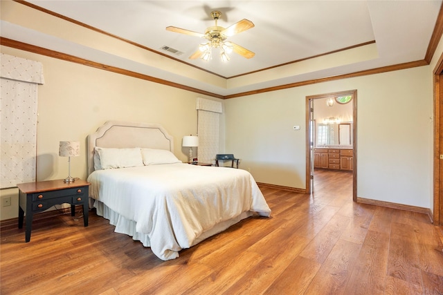 bedroom with visible vents, crown molding, baseboards, light wood-style floors, and a tray ceiling