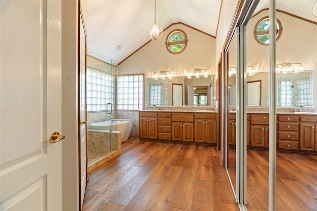 full bathroom with a freestanding bath, vanity, wood finished floors, lofted ceiling, and a stall shower
