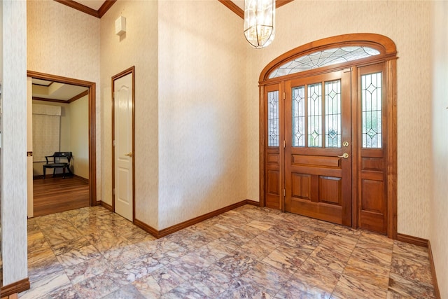foyer with crown molding, a chandelier, marble finish floor, baseboards, and a towering ceiling