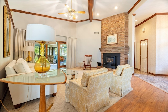 living area with ceiling fan, a stone fireplace, visible vents, crown molding, and wood finished floors