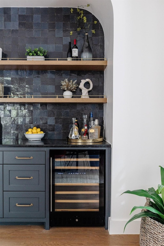 bar with wood finished floors, a bar, and wine cooler