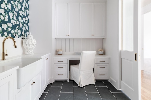 office space with built in study area, dark tile patterned floors, and a sink