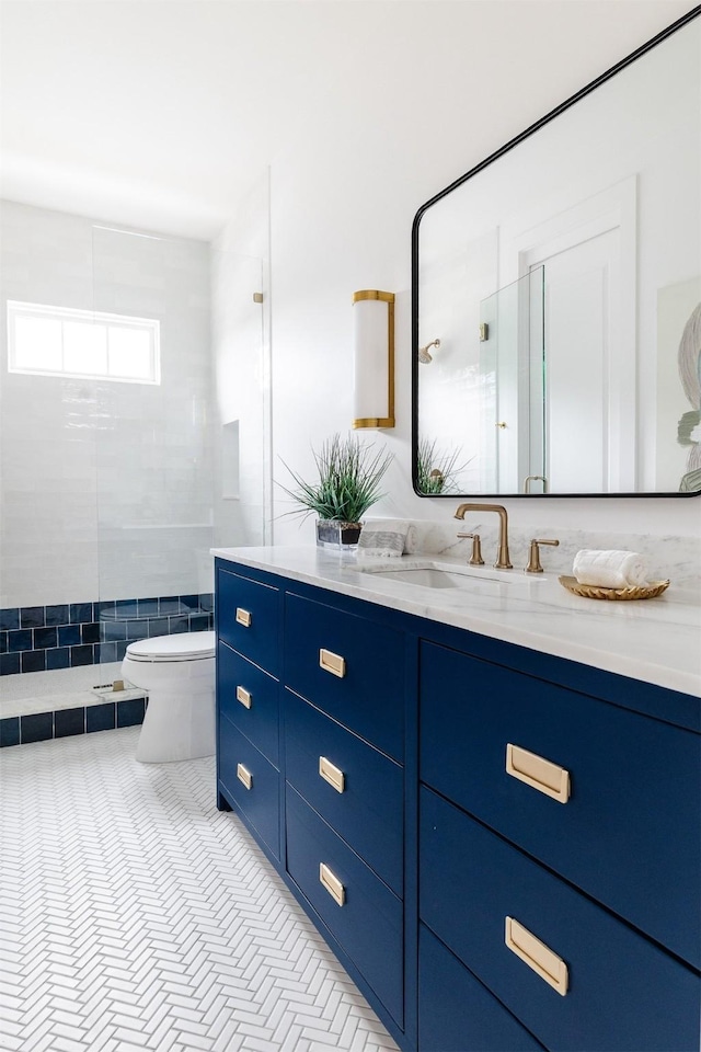 bathroom featuring tile patterned floors, vanity, toilet, and tiled shower