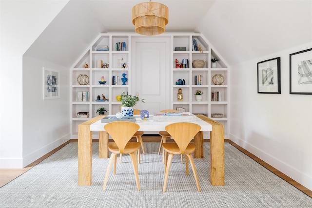 dining room featuring baseboards, lofted ceiling, and light wood-type flooring