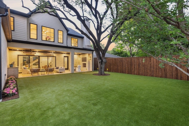 rear view of property featuring ceiling fan, a fenced backyard, an outdoor living space, brick siding, and a yard