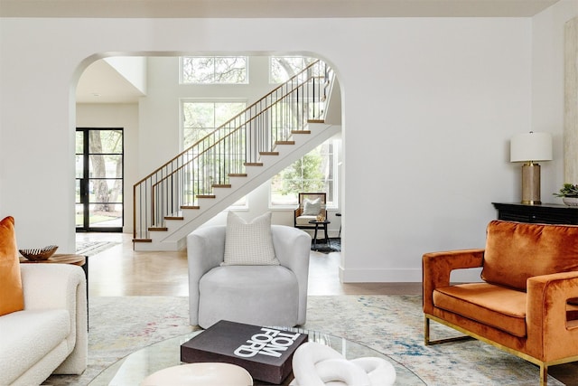 living room featuring stairs, arched walkways, plenty of natural light, and wood finished floors