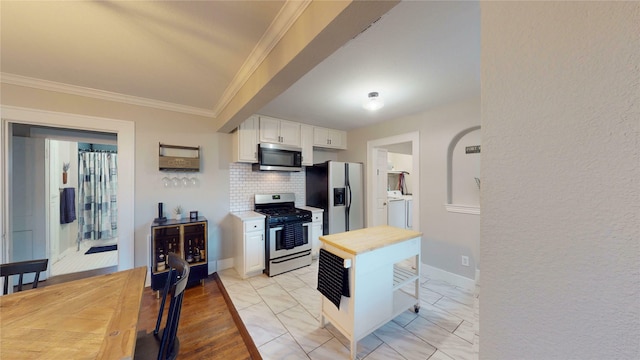 kitchen with crown molding, butcher block counters, white cabinets, backsplash, and stainless steel appliances