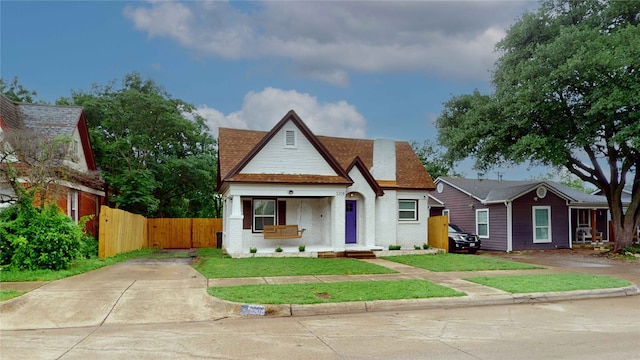view of front of home with brick siding, fence, driveway, and a front yard