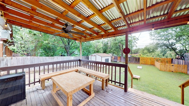 wooden deck with an outdoor structure, a fenced backyard, a shed, and a yard