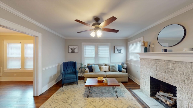 living room featuring ornamental molding, wood finished floors, a fireplace, baseboards, and ceiling fan
