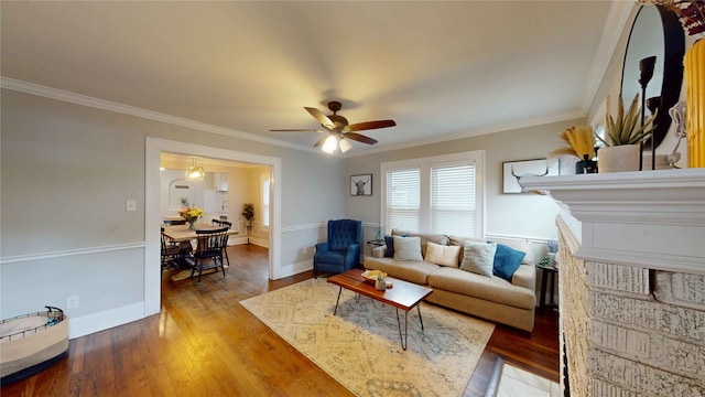 living room featuring crown molding, a ceiling fan, baseboards, and wood finished floors