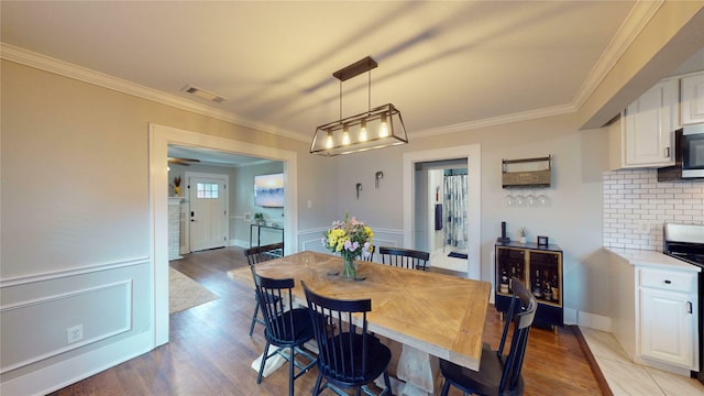 dining space featuring crown molding, visible vents, and light wood finished floors