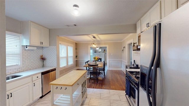 kitchen with wooden counters, tasteful backsplash, a sink, ornamental molding, and stainless steel appliances