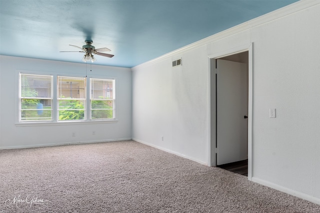 empty room featuring crown molding, carpet flooring, baseboards, and a ceiling fan
