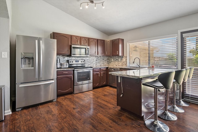 2036 Apple Valley Rd, Plano, TX 75023 - kitchen with a kitchen breakfast bar, decorative backsplash, appliances with stainless steel finishes, vaulted ceiling, and a peninsula