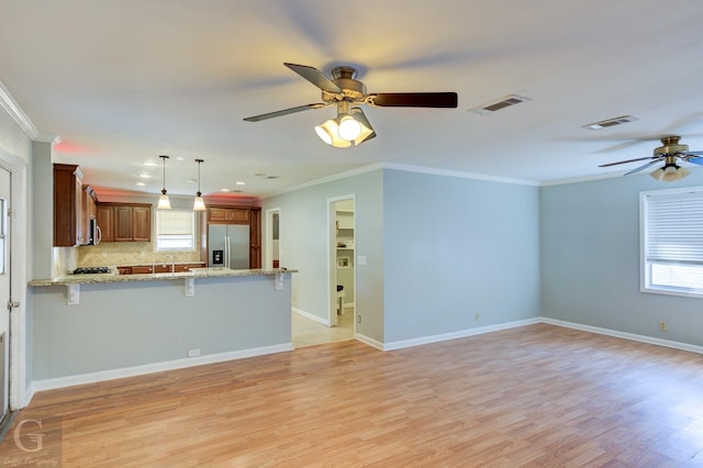 unfurnished living room featuring crown molding, visible vents, baseboards, a ceiling fan, and light wood-style flooring