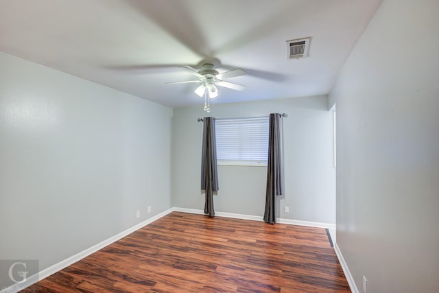 empty room with visible vents, dark wood-type flooring, baseboards, and ceiling fan