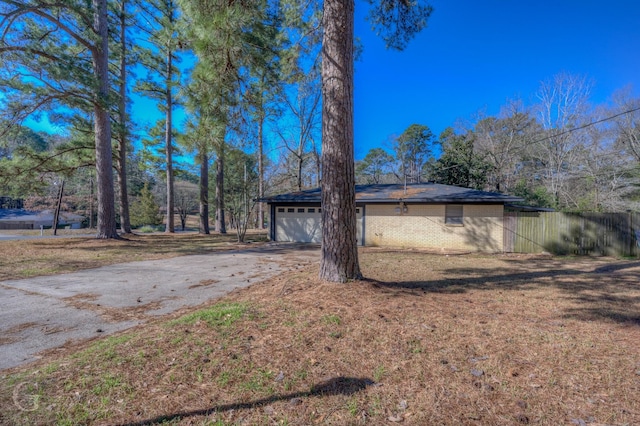 view of property exterior featuring an attached garage, driveway, and brick siding