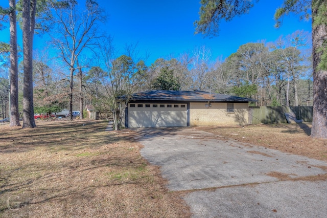 view of home's exterior with brick siding, a garage, aphalt driveway, and fence