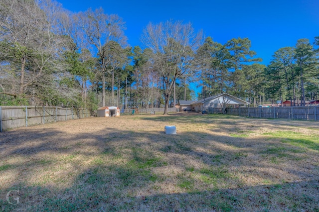 view of yard featuring a fenced backyard, a storage unit, and an outbuilding