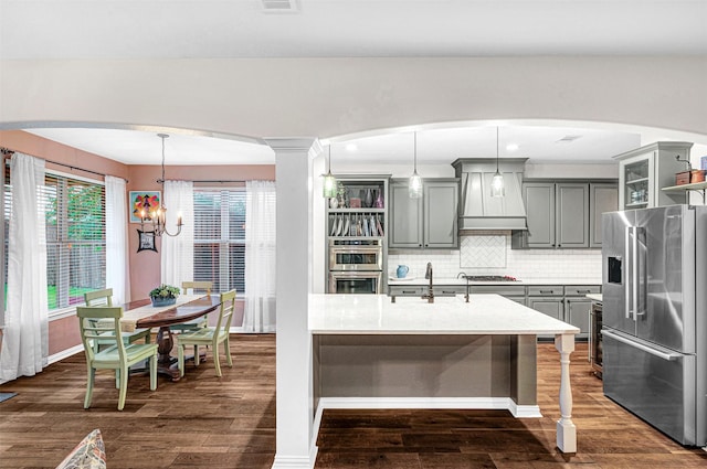 kitchen featuring appliances with stainless steel finishes, gray cabinetry, light countertops, custom exhaust hood, and a chandelier