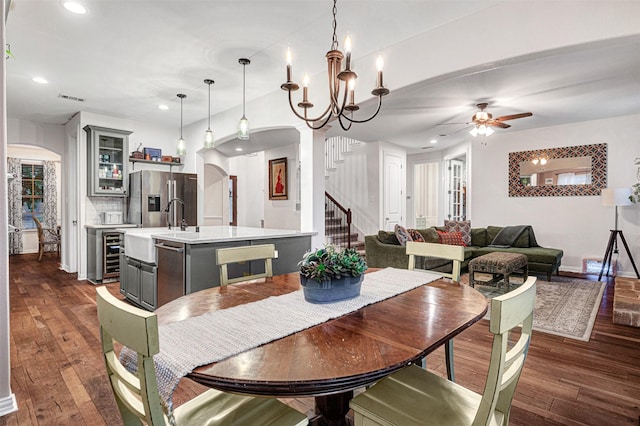 dining space with wine cooler, visible vents, stairway, arched walkways, and dark wood-style floors