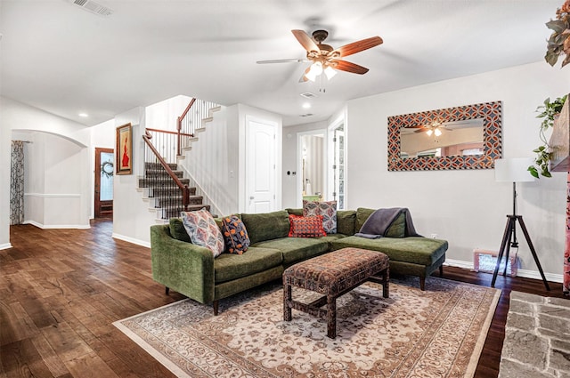 living area with wood-type flooring, a ceiling fan, stairs, and visible vents