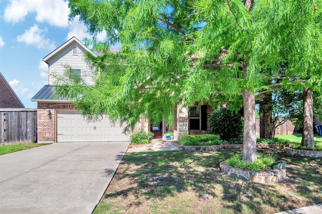 obstructed view of property featuring an attached garage, fence, brick siding, driveway, and a standing seam roof