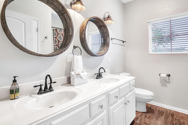 full bathroom featuring double vanity, a sink, wood finished floors, and toilet