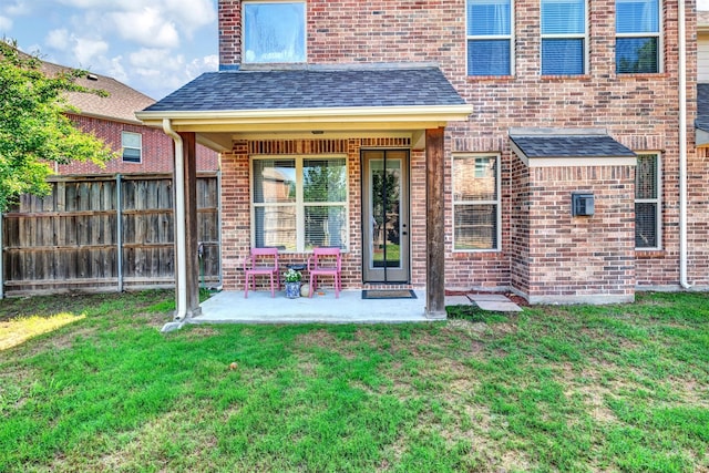 exterior space featuring a patio area, fence, brick siding, and a lawn